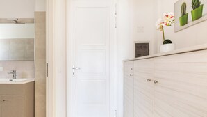 A modern bathroom with a white door, a sink, and a mirror. There are potted plants on the counter. - 3951 Mono di Annahouse by Barbarhouse (Porto Cesareo)