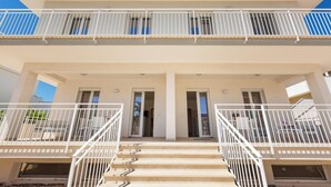 A two-story building with a balcony on the upper floor, a set of stairs leading to the entrance, and a door with a window on the ground floor. - 3951 Mono di Annahouse by Barbarhouse (Porto Cesareo)