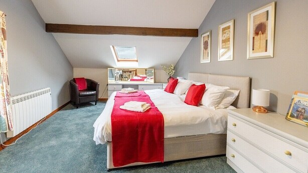 A bedroom with a large bed, a desk, and a chair.