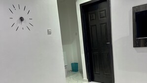 A modern living room with a white coffee table, two blue sofas, a black door, and a wall clock. - Blueocean.cog Apartments (Benin City)