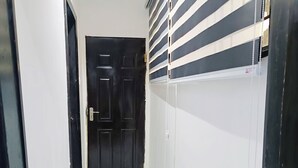 A narrow hallway with a black door at the end, white walls, and a tiled floor. - Blueocean.cog Apartments (Benin City)