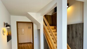 A modern interior with a wooden staircase, a welcome sign, and a light fixture. - Large Holiday Home for Groups up to 17 Guests with Hot Tub & Playroom (Herbstein)