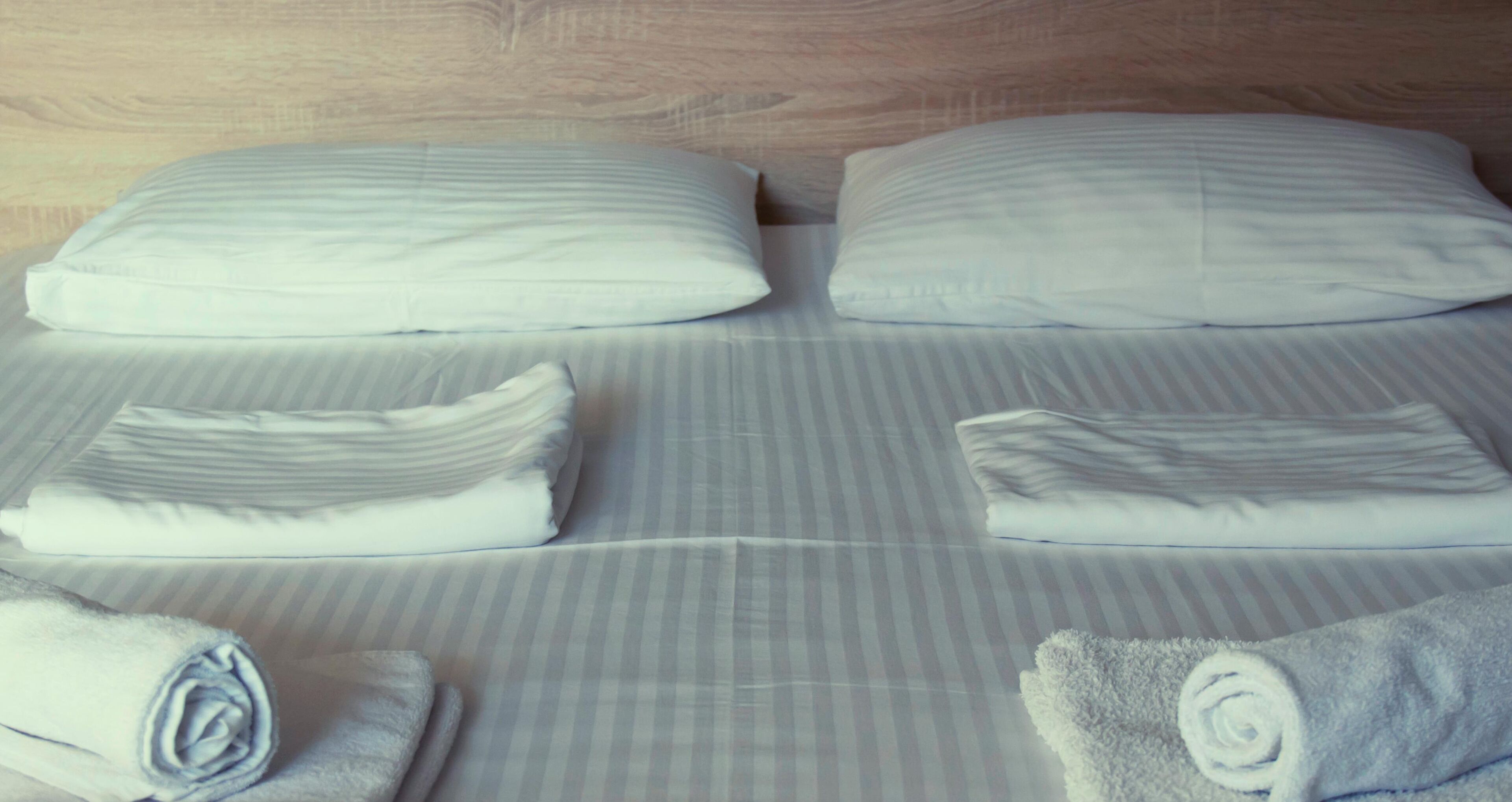 Una cama bien hecha con ropa de cama a rayas y toallas enrolladas.