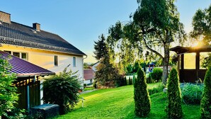 A residential property with a well-maintained lawn, a wooden deck, and a garden with neatly trimmed bushes and trees. - Large Holiday Home for Groups up to 17 Guests with Hot Tub & Playroom (Herbstein)