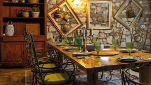 Un comedor con pared de piedra, muebles de madera y cuadros enmarcados.