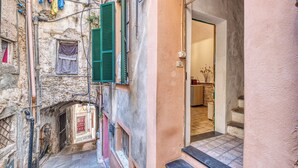 A narrow alleyway with a stone building, a wooden door, and a small window with a shutter. - Caratteristico Appartamento In Centro (Sanremo)