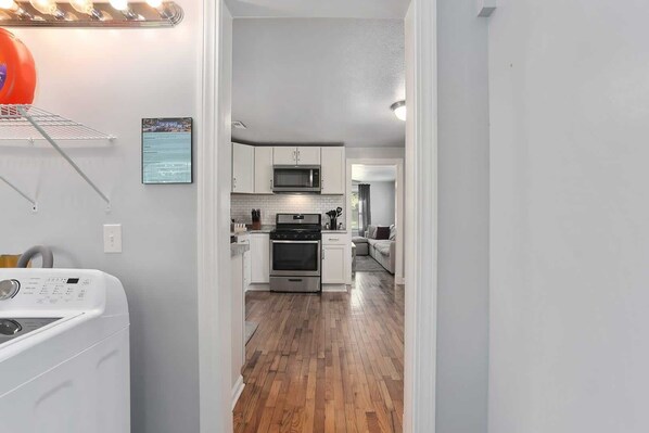 A modern kitchen with white cabinets, stainless steel appliances, and a wooden floor.