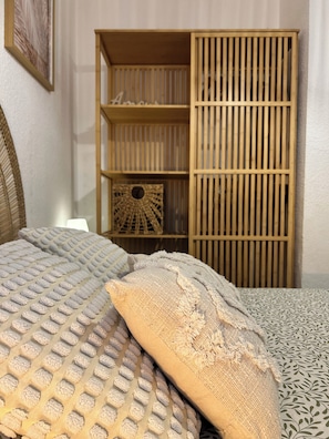 Un letto con cuscini decorati e un'armadio in legno con scomparti multipli.