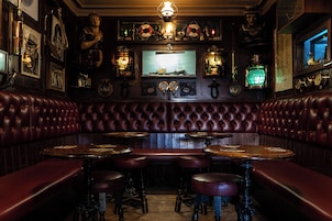A vintage bar with leather booths, wooden tables, and brass fixtures.