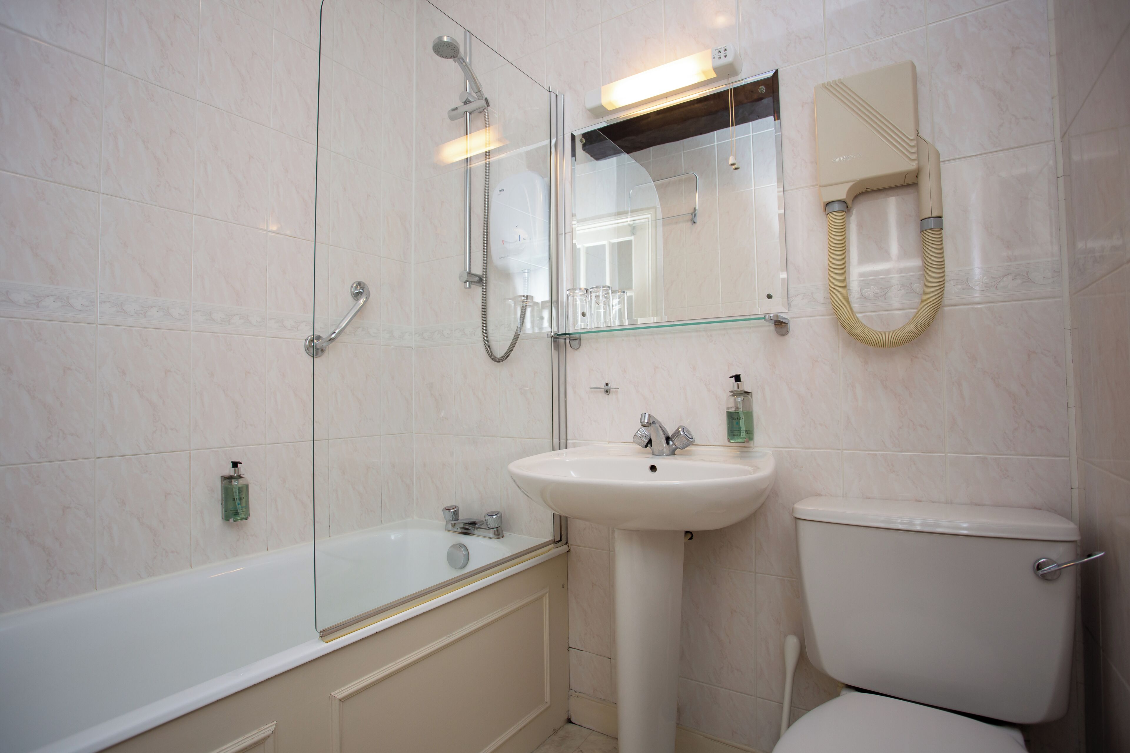 A bathroom with a glass-enclosed shower, a pedestal sink, and a toilet.