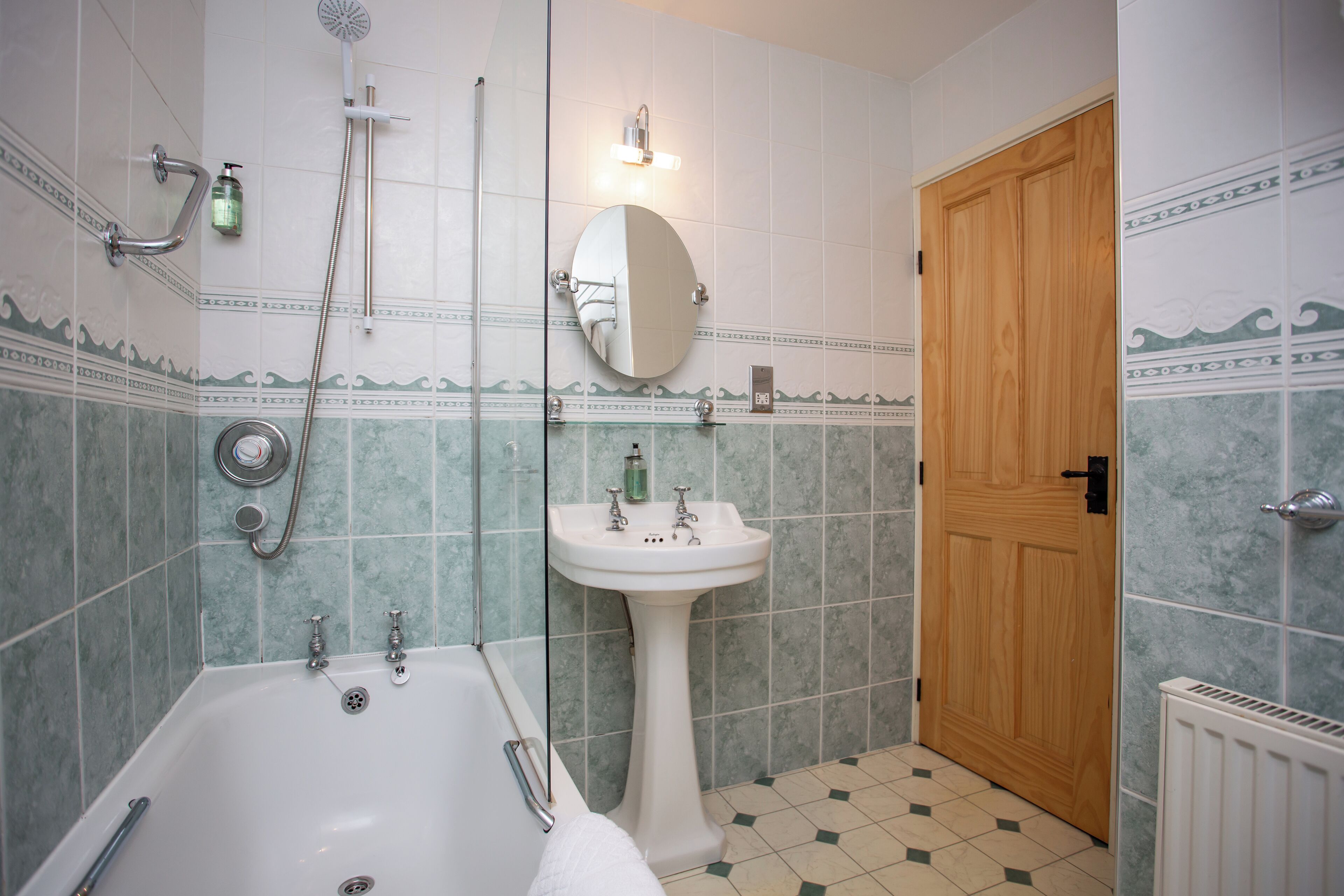 A bathroom with a bathtub, a sink, a mirror, and a shower.