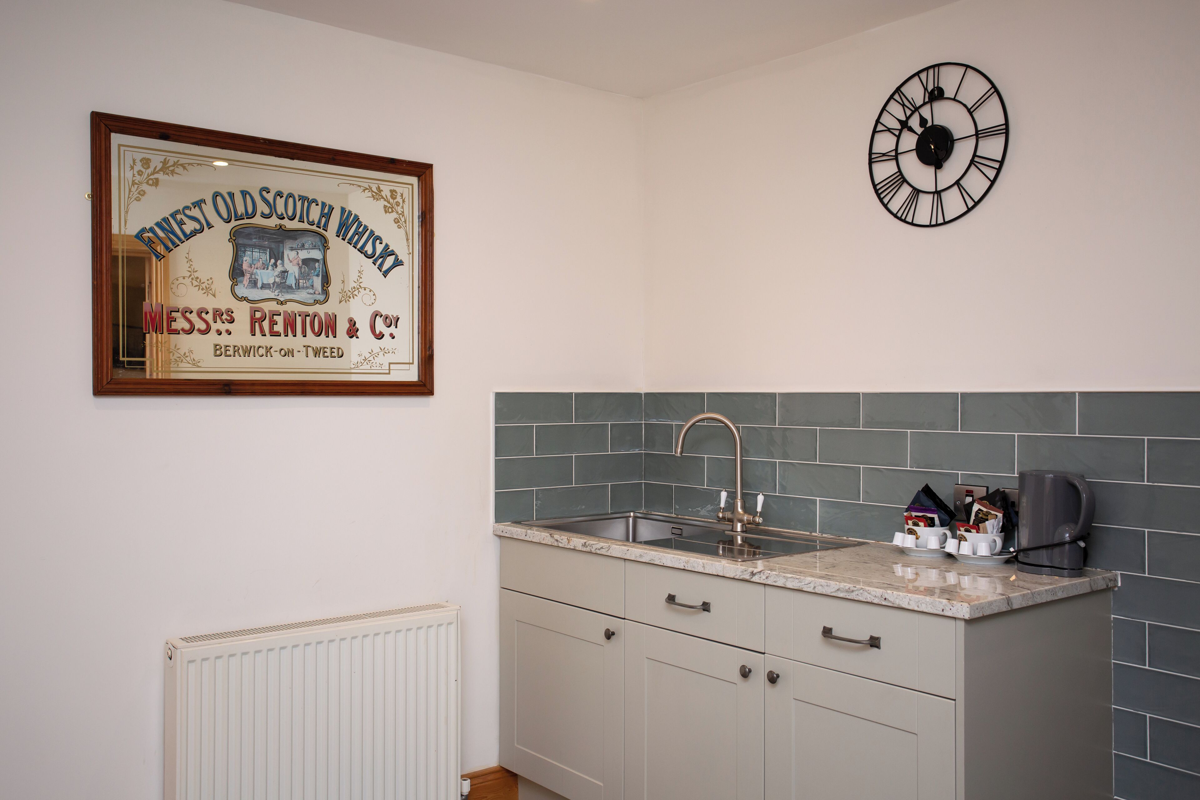 A kitchen with a sink, countertop, and a clock on the wall.