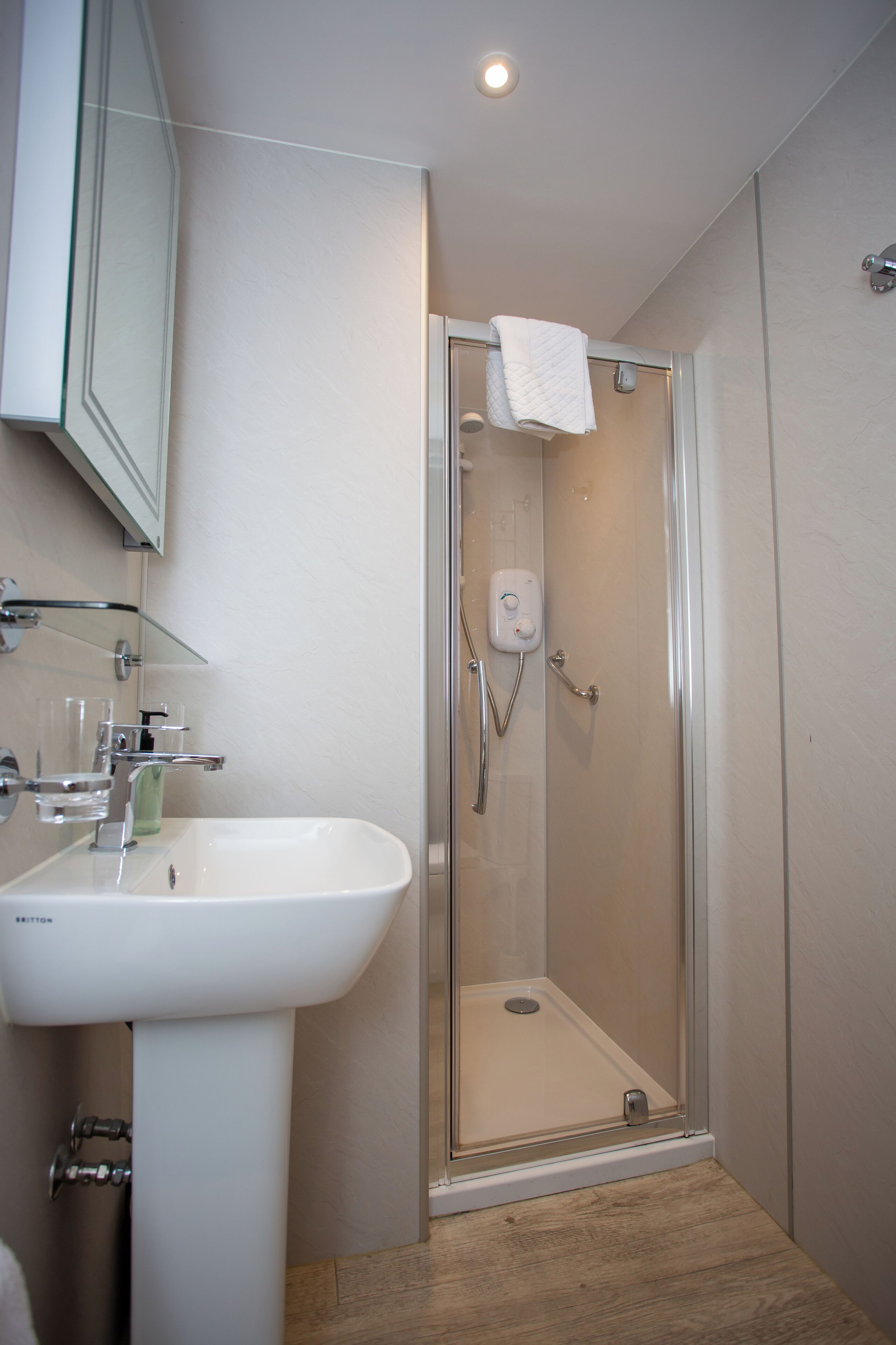 A modern bathroom with a glass-enclosed shower, a white sink, and a glass shower door.