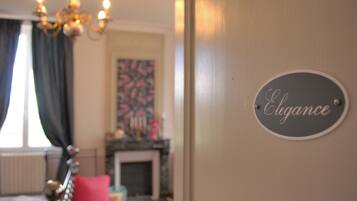 A room with a bed, a chandelier, a fireplace, and a sign that reads "Elegance".