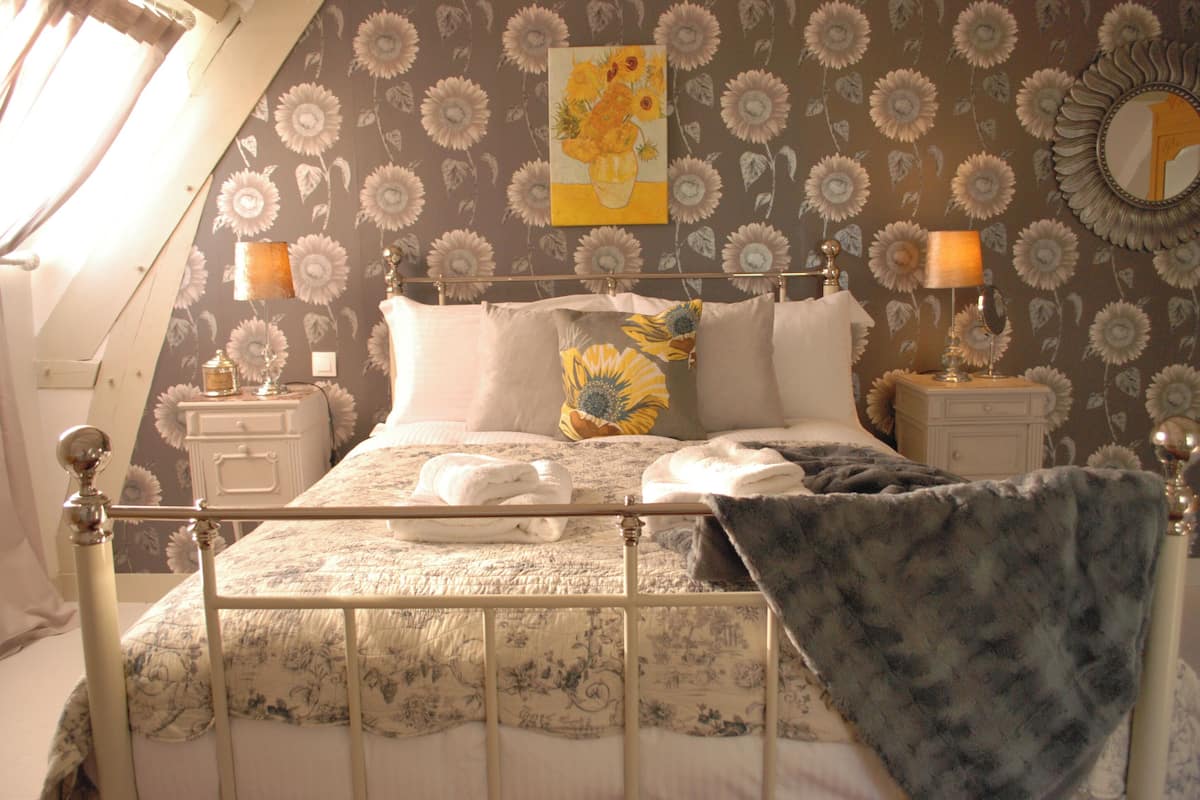 Un dormitorio con cama, dos mesitas de noche, un espejo y una ventana con cortinas.