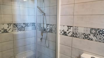 Un baño con ducha, inodoro y paredes de azulejos.