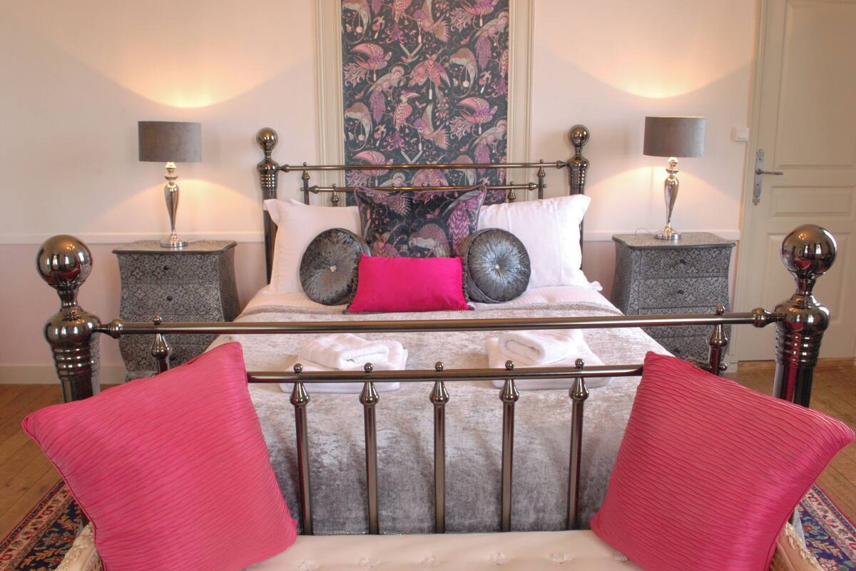 Una cama con estructura metálica, dos mesitas de noche y un tapiz decorativo en la pared.