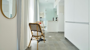 Une cuisine moderne avec des meubles blancs, un coin repas comprenant une chaise et une table, et un grand miroir au mur.