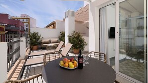 Un balcon avec une table dressée pour le dîner, une plante en pot et une bouteille de vin.