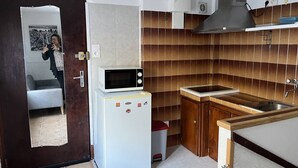 A compact kitchen with a microwave, refrigerator, sink, and wooden cabinets.