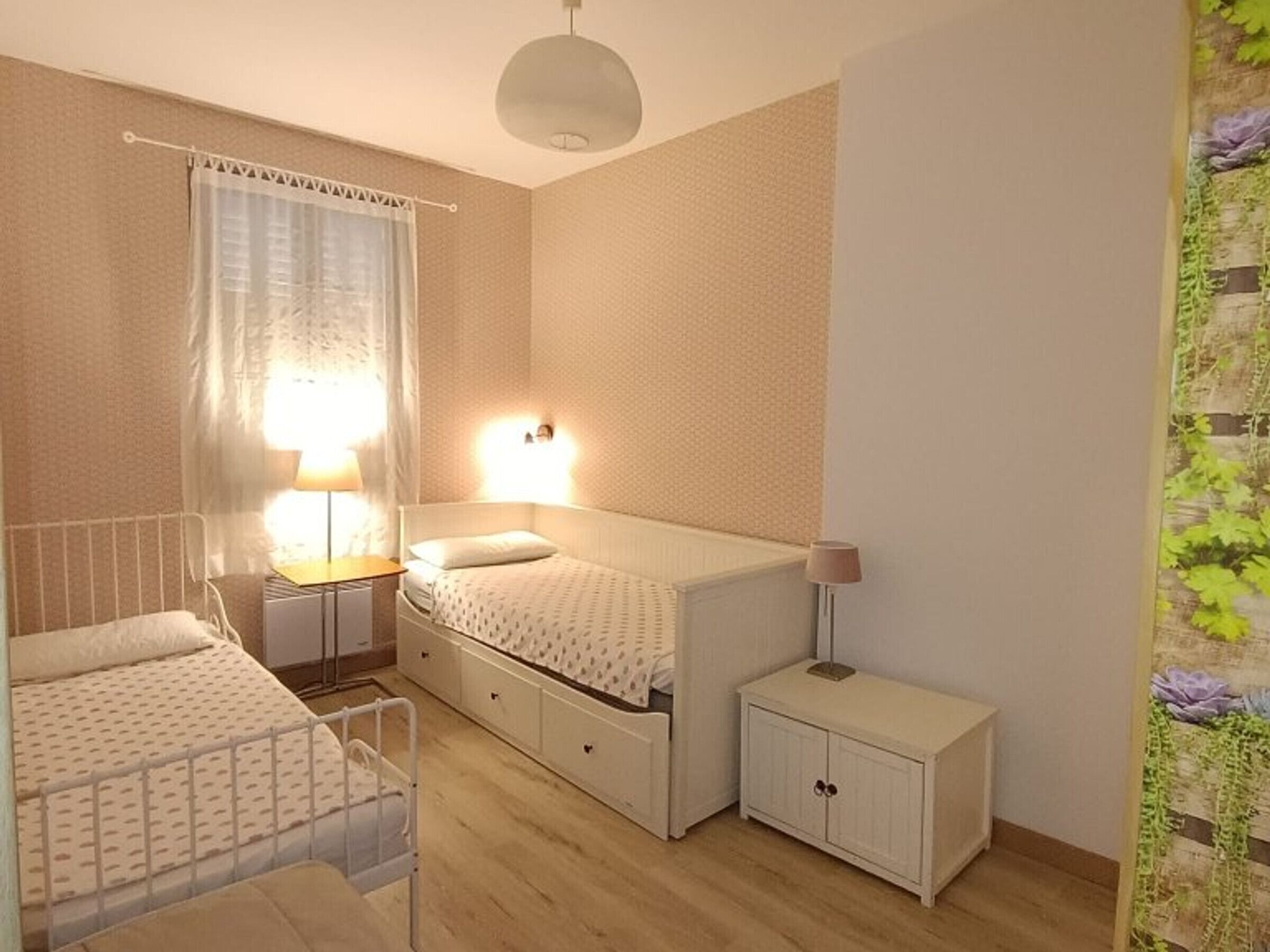 Un dormitorio pequeño y bien iluminado, con una cama individual, mesitas de noche y un armario.