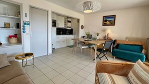 Ein modernes Wohnzimmer mit einer Couch, einem Esstisch und einer Küche im Hintergrund.
