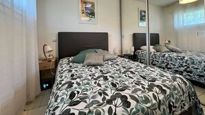 Ein Schlafzimmer mit zwei Betten, einem großen Spiegel und einem Nachttisch mit einer Lampe.