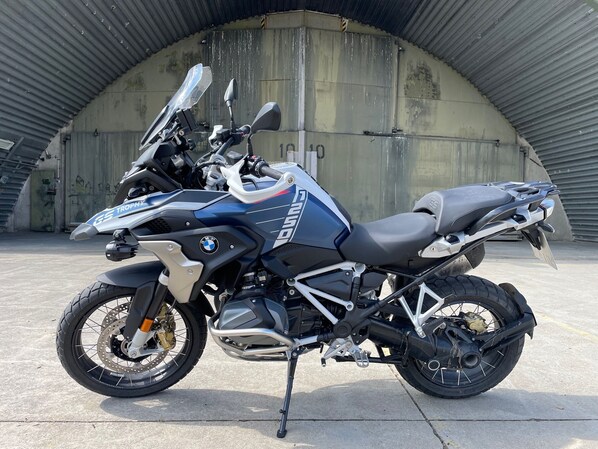 A BMW motorcycle parked in a covered area with a concrete floor.