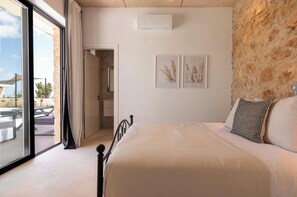 A bedroom with a bed, a stone wall, and a view of the outdoors.