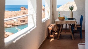 Una terrazza con un tavolo apparecchiato per mangiare, affacciata su un litorale roccioso.