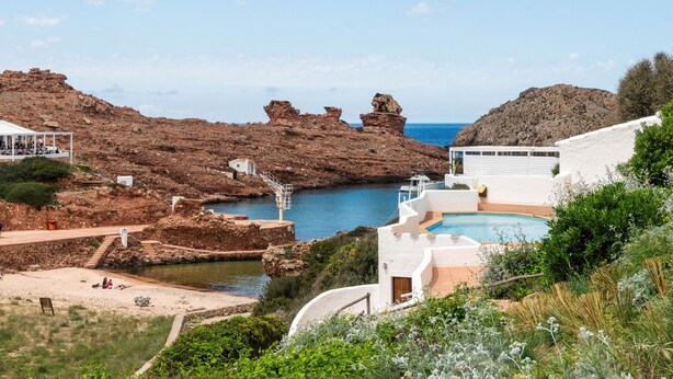 Una località balneare con piscina, scogliere rocciose e vista sul mare.