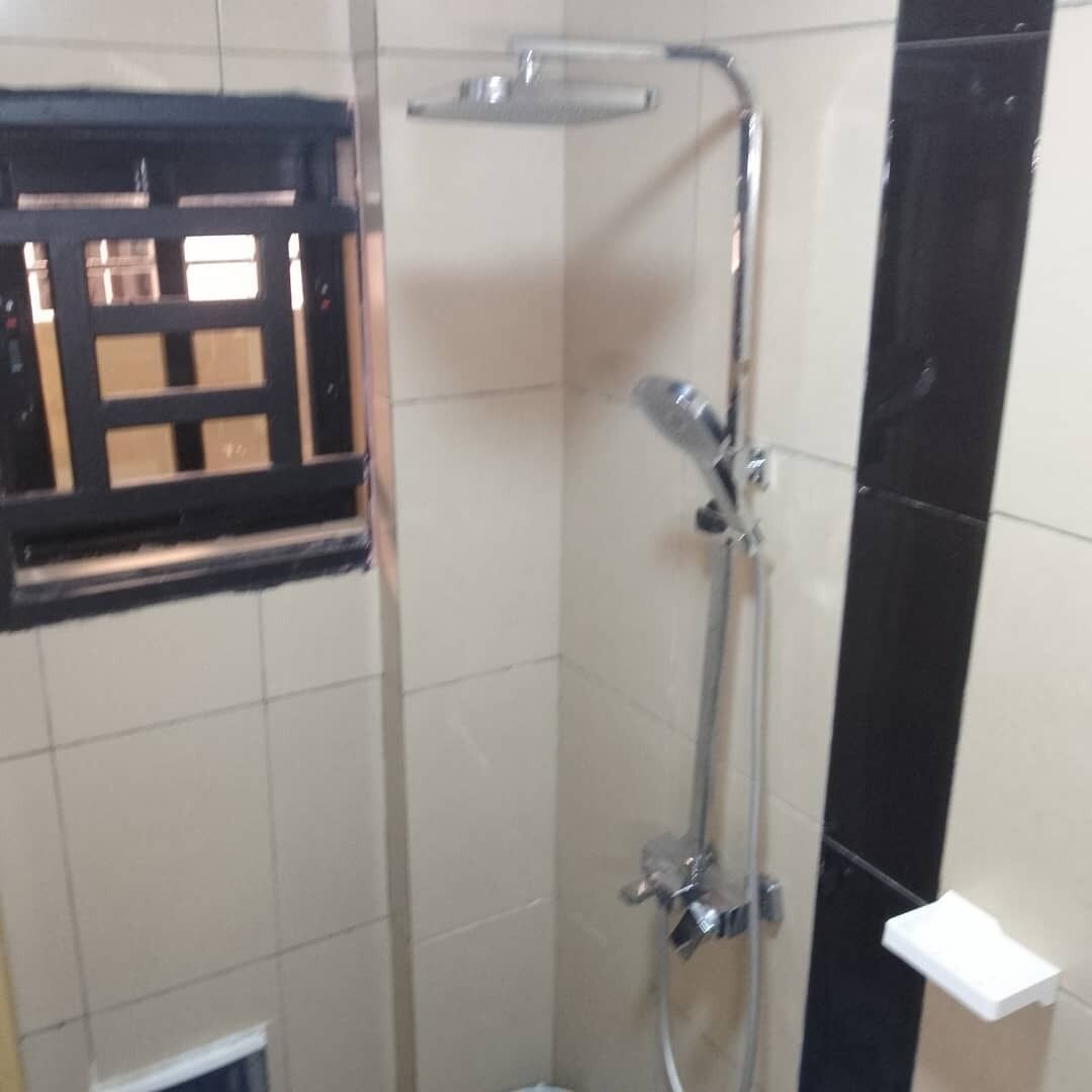 A shower area with a handheld showerhead and a wall-mounted faucet.