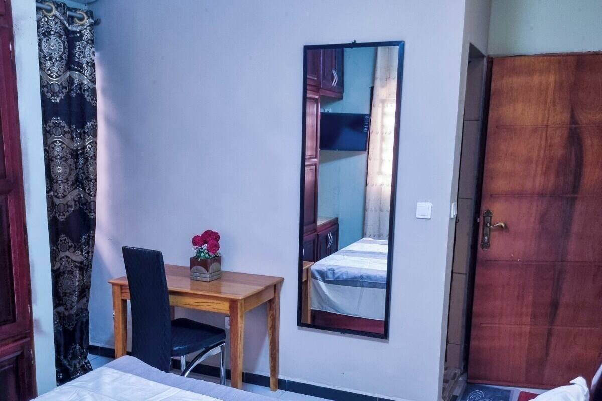 A hotel room with a bed, a desk, a chair, a mirror, and a wardrobe.