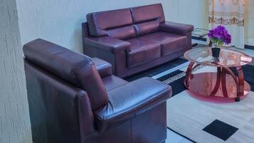 A living room with a brown leather sofa, a glass coffee table, and a framed picture on the wall.