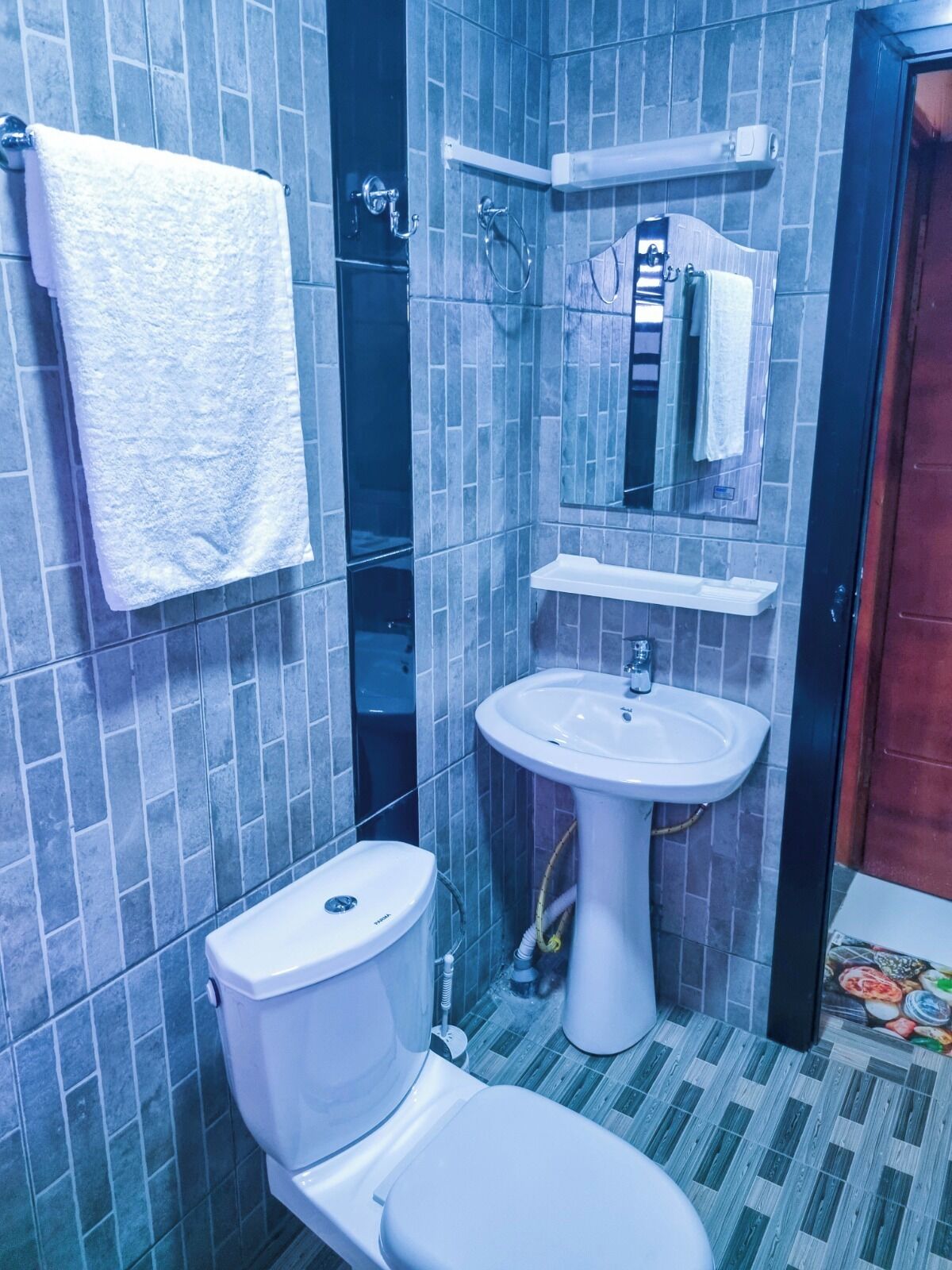 A bathroom with a toilet, sink, and mirror.
