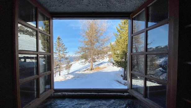 A room with a large window revealing a snowy outdoor scene with trees and a clear sky. - Chalet 12 Personne - Seul au Monde (Vars)