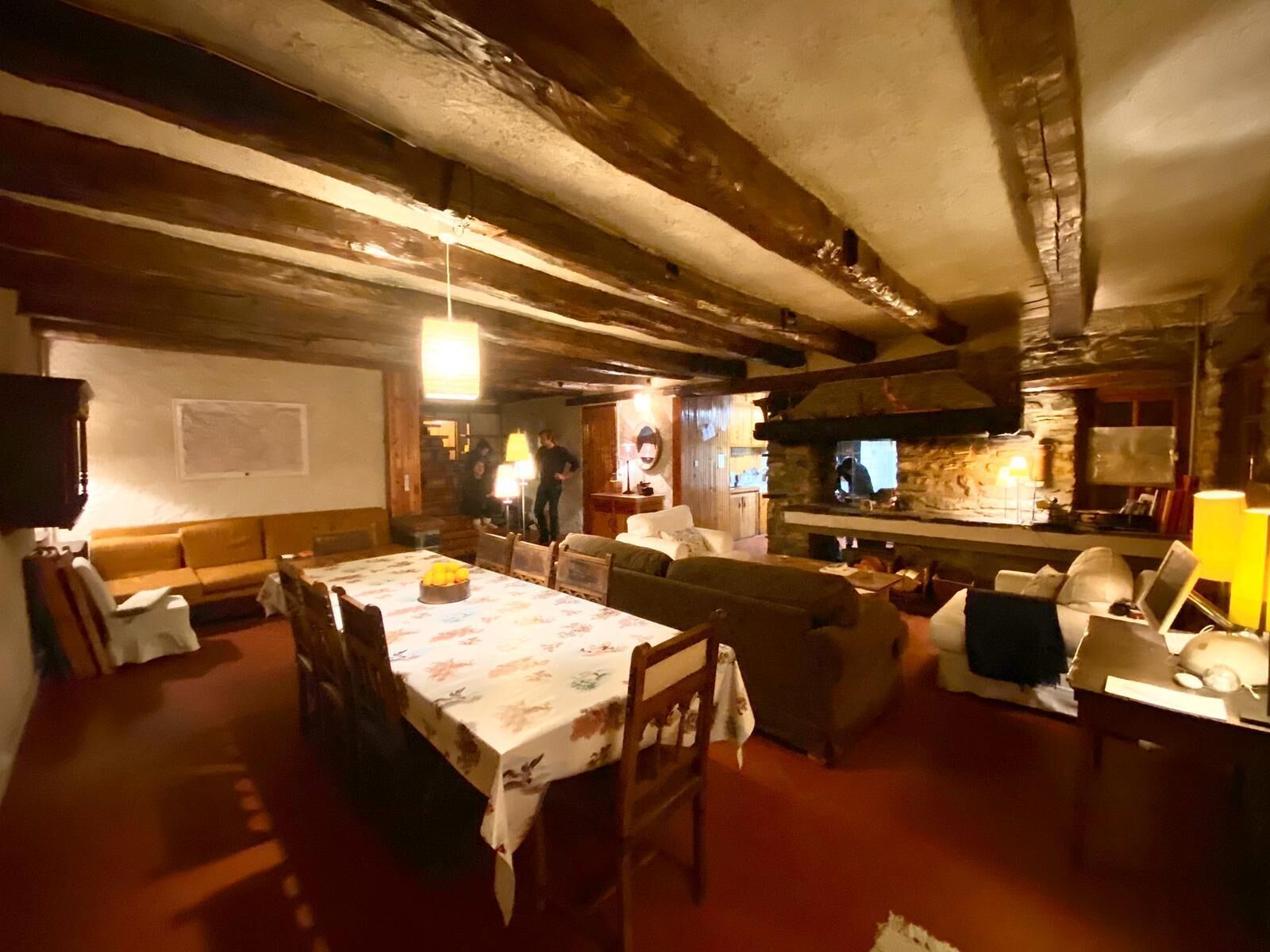 A cozy, rustic dining area with a wooden table and chairs, a sofa, and a stone fireplace.