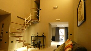 A living room with a staircase, a sofa, a small table with bottles, and a window. - Antique dwelling, strategically located for Naples, Sorrento, Pompeii, Positano. (Portici)