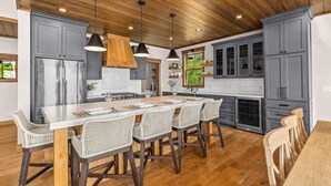 A modern kitchen with grey cabinets, a large island with bar stools, and wooden flooring. - NEW! Cross Lake's Finest! (Crosslake)