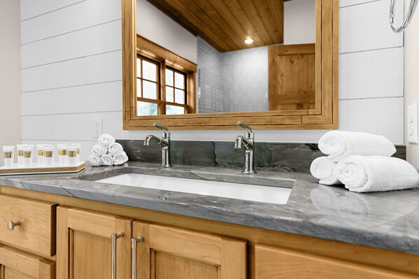 A bathroom with a large sink, wooden cabinets, and a mirror. - NEW! Cross Lake's Finest! (Crosslake)