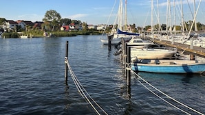 Un port de plaisance où plusieurs bateaux sont amarrés, l’eau est calme et le ciel est d’un bleu limpide.