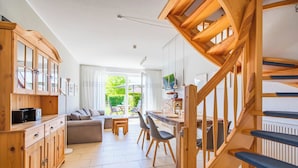 Une cuisine spacieuse avec des meubles en bois, un coin repas comprenant une table et des chaises, et un escalier avec des marches bleues.