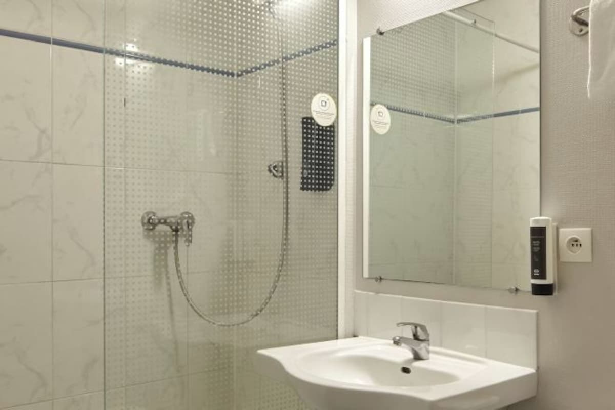 Un baño moderno con cabina de ducha de vidrio, un lavabo blanco y un espejo.