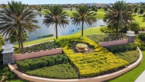 A resort with a well-maintained garden, palm trees, and a lake view. - Kissimmee Villa: 9BR Oasis, Sleeps 16 (Kissimmee)
