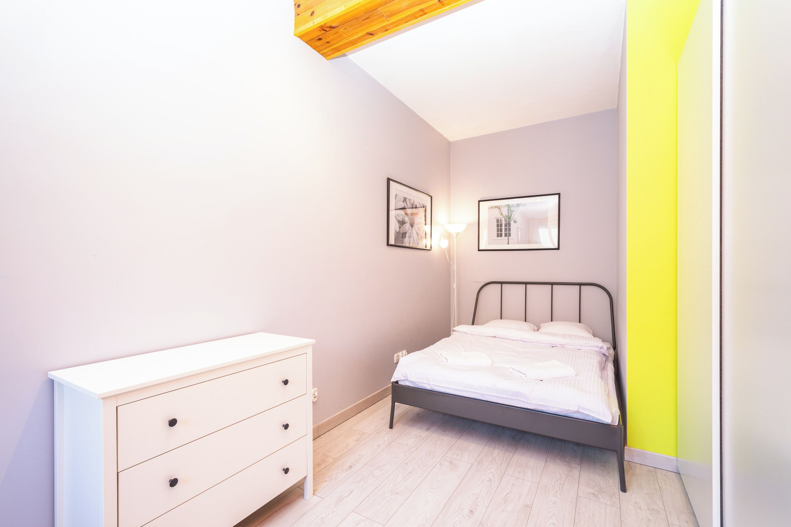 Ein Schlafzimmer mit einem Bett, einem Schminktisch und zwei gerahmten Bildern an der Wand.