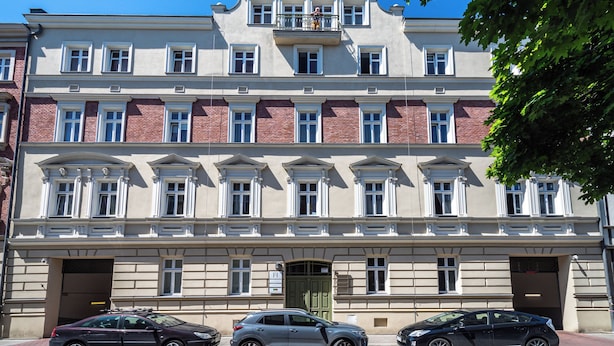 Un immeuble à plusieurs étages, doté d’une façade symétrique, de grandes fenêtres et d’une entrée centrale.