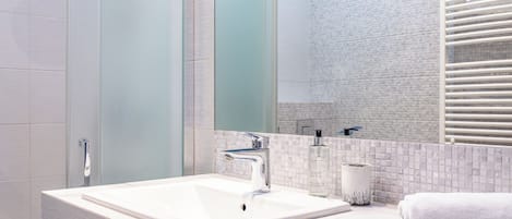 A modern bathroom with a large mirror, a white sink, and a towel.