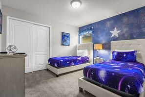 Un dormitorio con dos camas, una mesita de noche, un aparador, un cartel y una estrella en la pared.