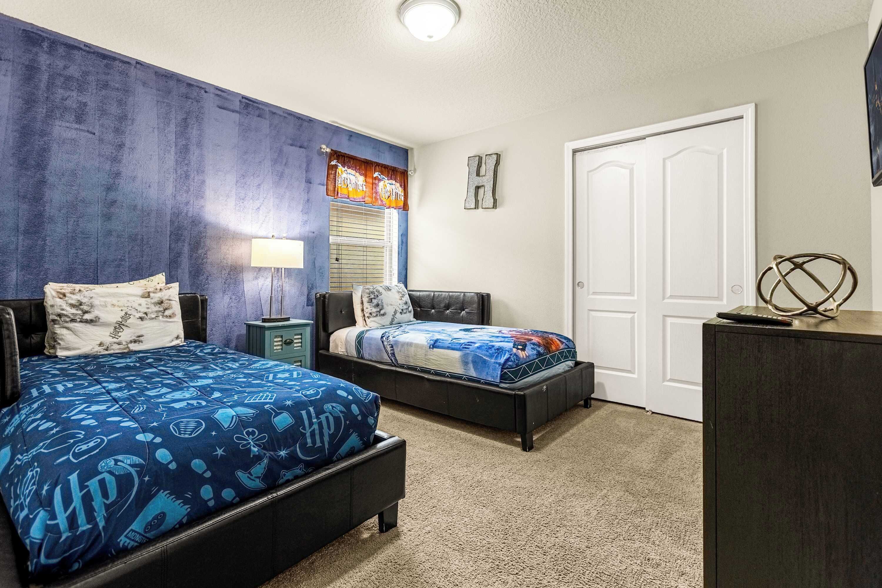 A bedroom with two beds, a nightstand, a dresser, and a door.