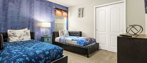 A bedroom with two beds, a nightstand, a dresser, and a door.